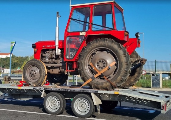 Roter Traktor verladen auf dem Autotransportanhänger der P.A.R.K GbR